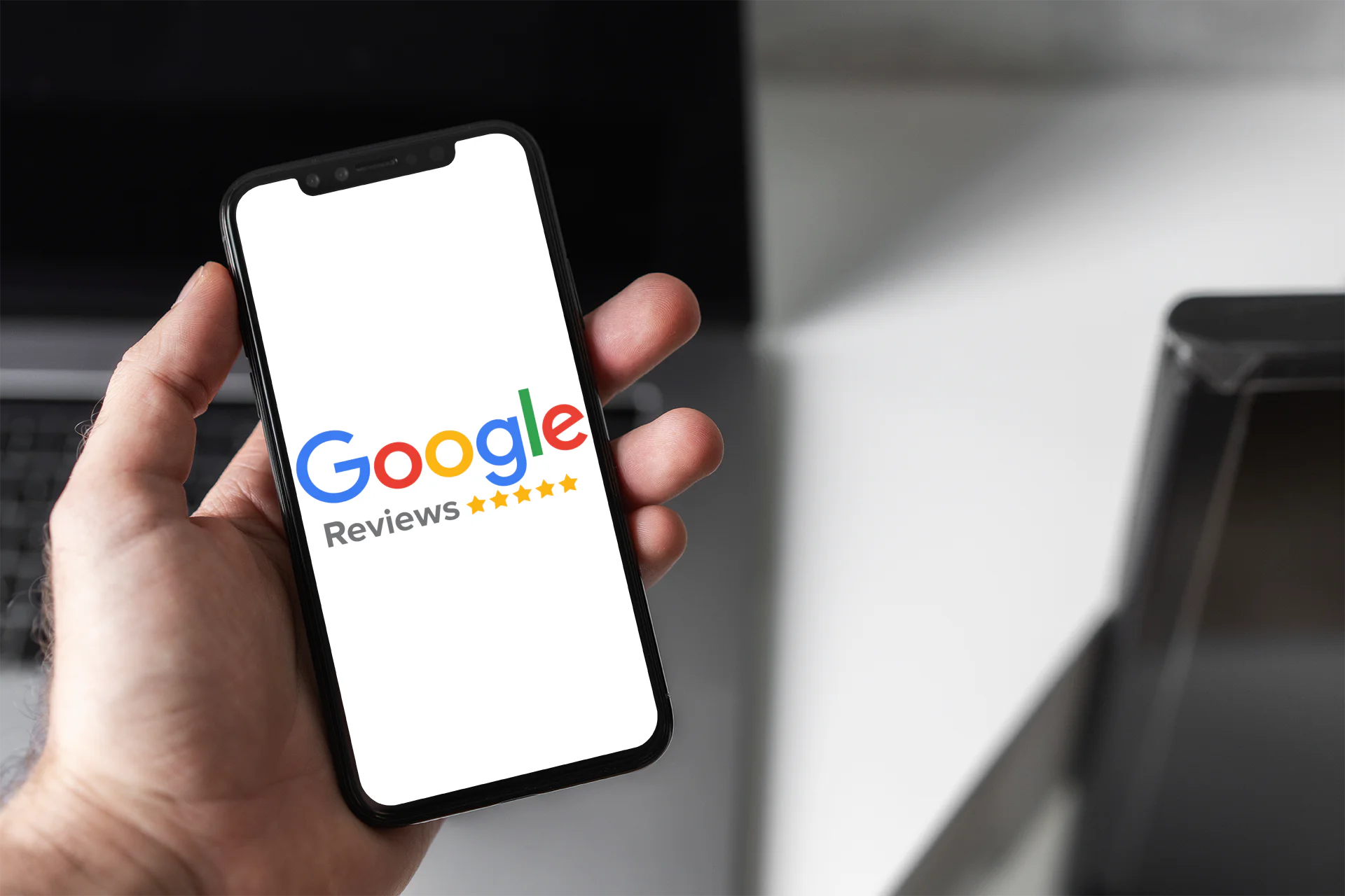 A mans hand holding an iPhone with a Google Reviews logo displayed